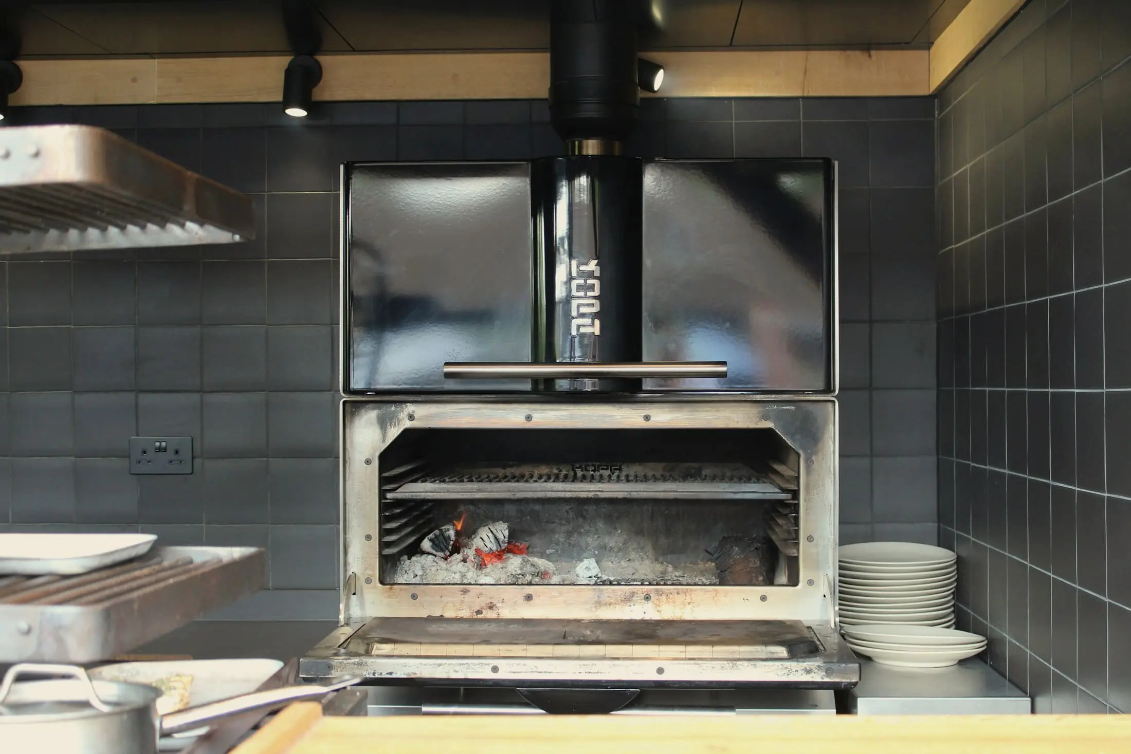 Stainless-steel wood-fired grill with a bed of white embers